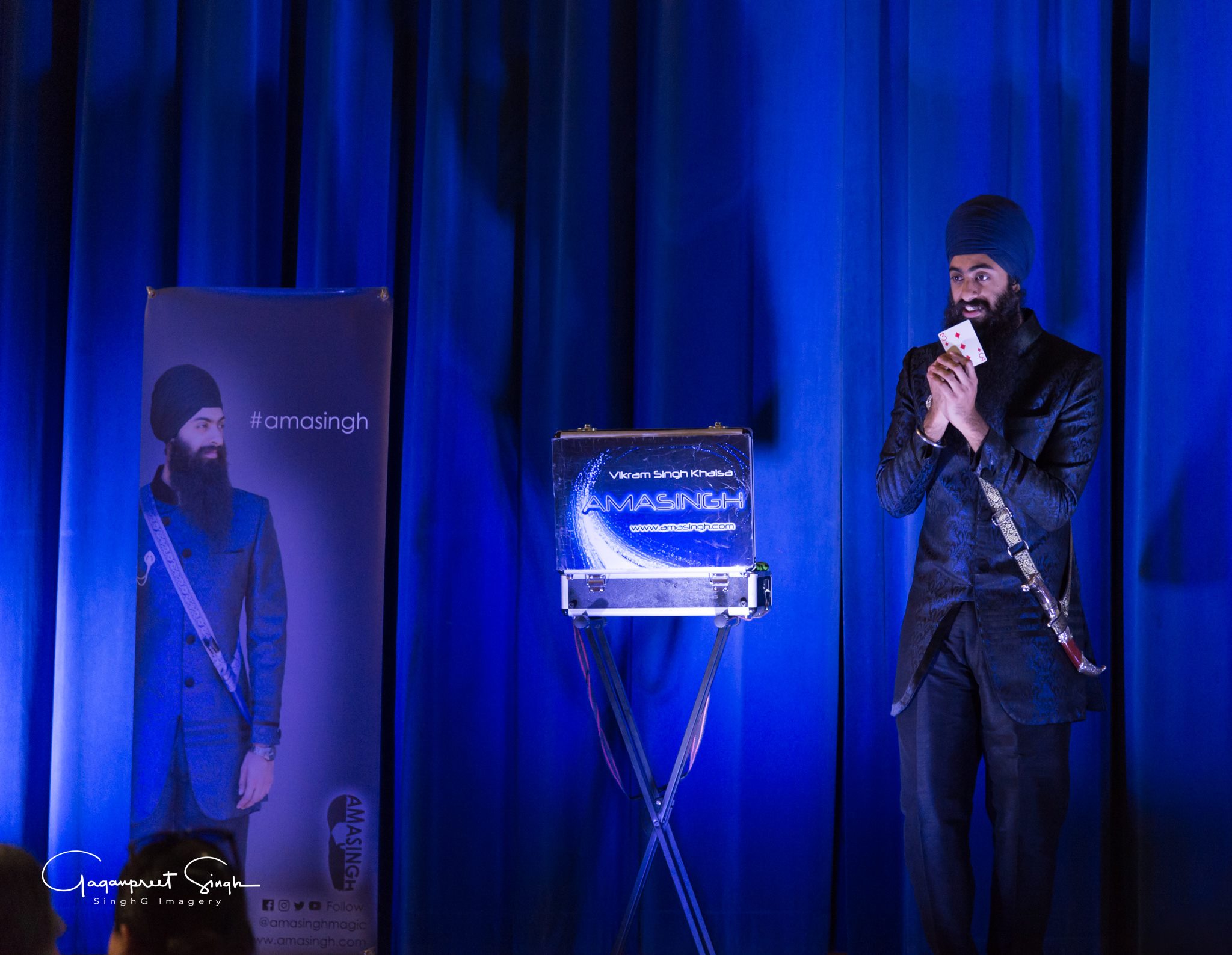 The Amasingh Magician performing a show on stage with bllue spotlights